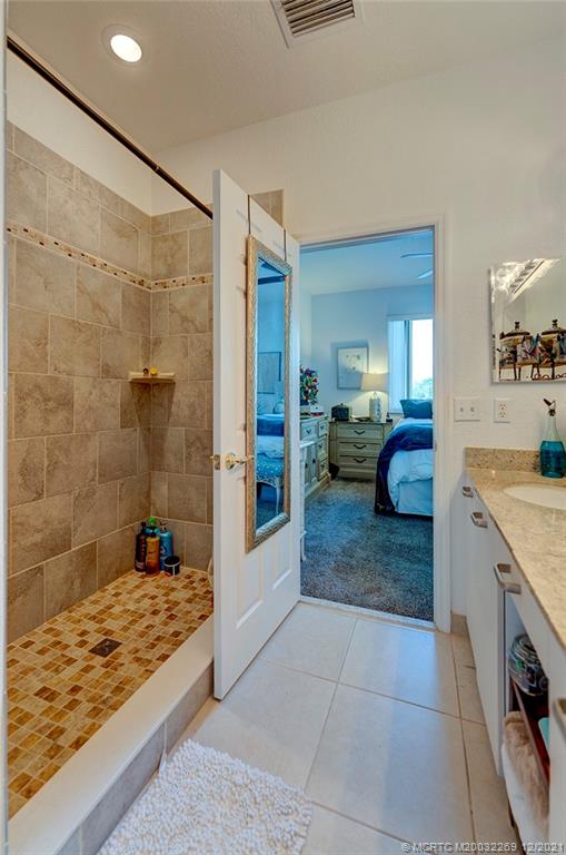 55 Southeast Palermo, Unit 102 Stuart, FL 34994 - Photo 11 of 40 a bathroom with a granite countertop sink a mirror and shower