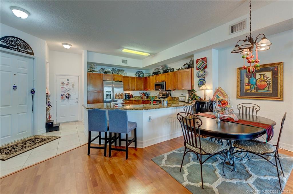 55 Southeast Palermo, Unit 102 Stuart, FL 34994 - Photo 23 of 40 a dining room with furniture a chandelier and wooden floor
