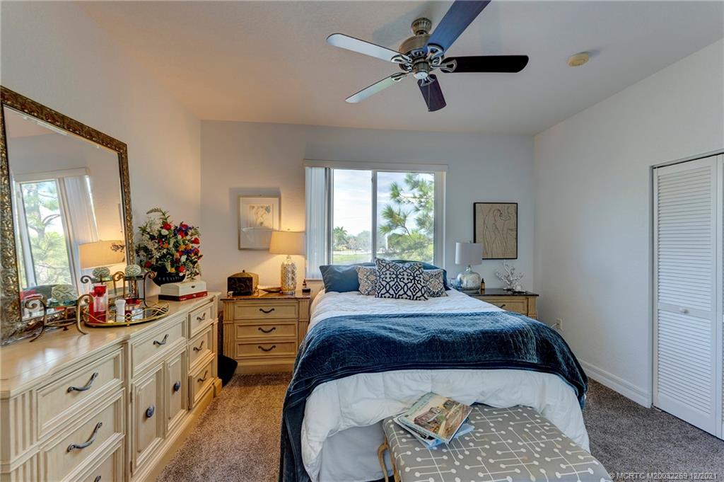 55 Southeast Palermo, Unit 102 Stuart, FL 34994 - Photo 9 of 40 a spacious bedroom with a bed a chandelier and dresser
