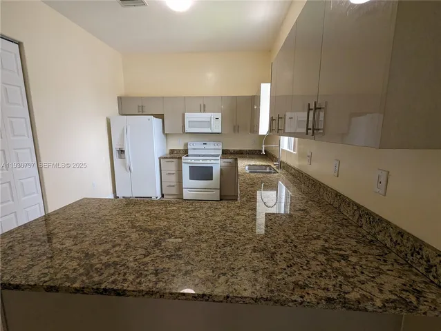a kitchen with stainless steel appliances granite countertop a sink refrigerator and stove