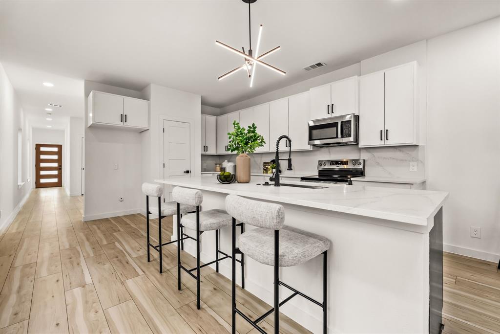 2232 Hooper Street Dallas, TX 75215 - Photo 6 of 23 a kitchen with stainless steel appliances a white table chairs refrigerator and microwave