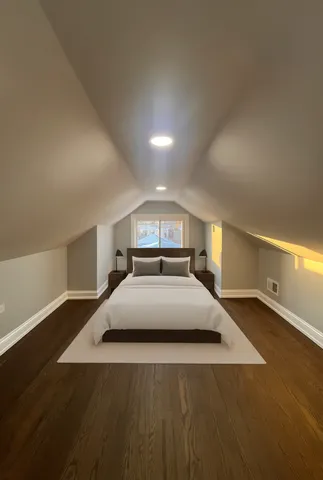 a spacious bedroom with a bed and a lamp on desk