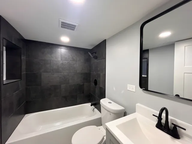 a bathroom with a toilet a sink a mirror and bathtub