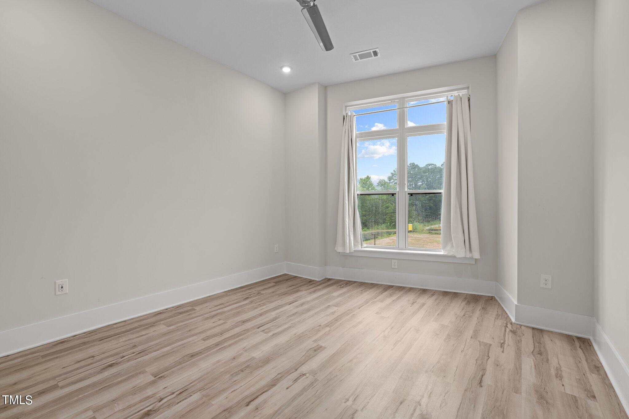 2441 Campus Shore Drive, Unit 312 Raleigh, NC 27606 - Photo 11 of 43 a view of an empty room with wooden floor and a window