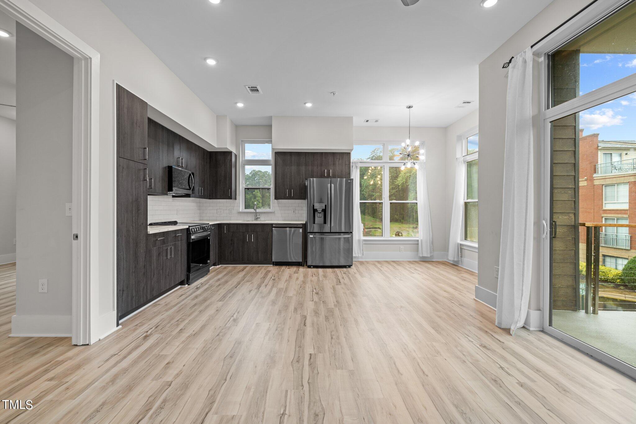 2441 Campus Shore Drive, Unit 312 Raleigh, NC 27606 - Photo 3 of 43 a large kitchen with kitchen island a island wooden floors stainless steel appliances and cabinets