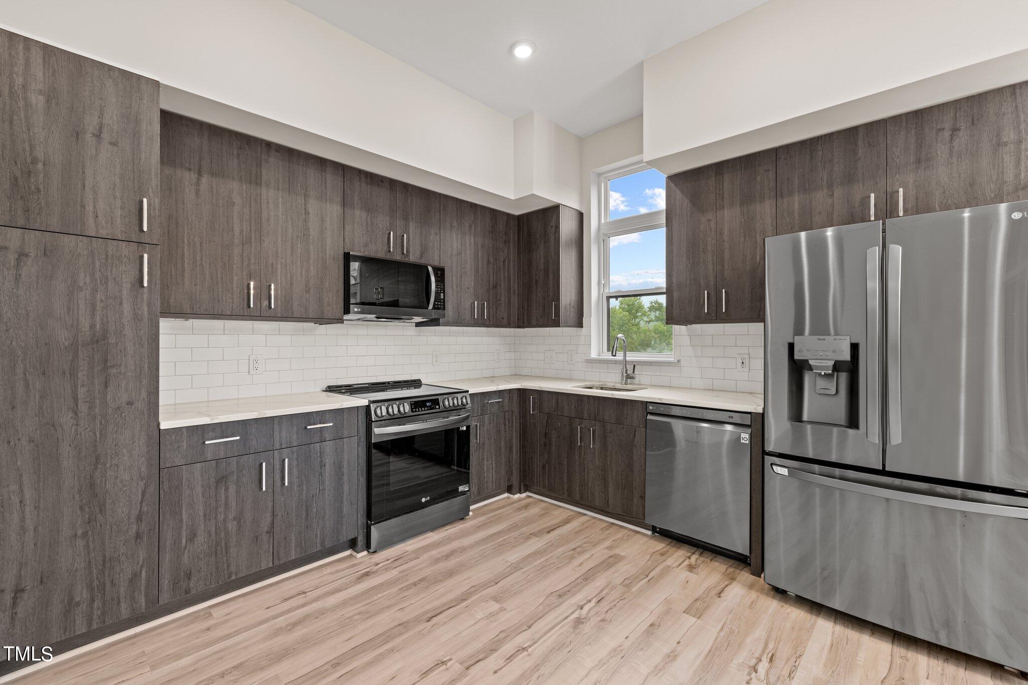 2441 Campus Shore Drive, Unit 312 Raleigh, NC 27606 - Photo 4 of 43 a kitchen with granite countertop a refrigerator stove top oven and sink