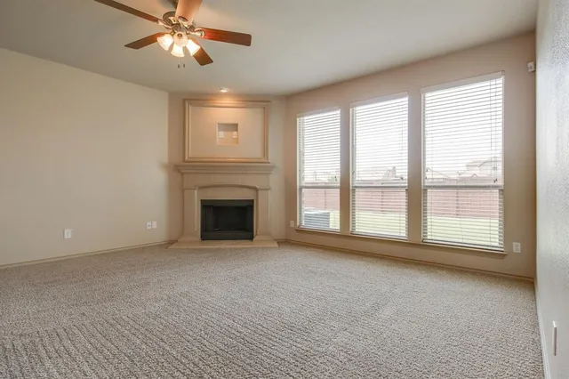 a view of an empty room with a window and a kitchen