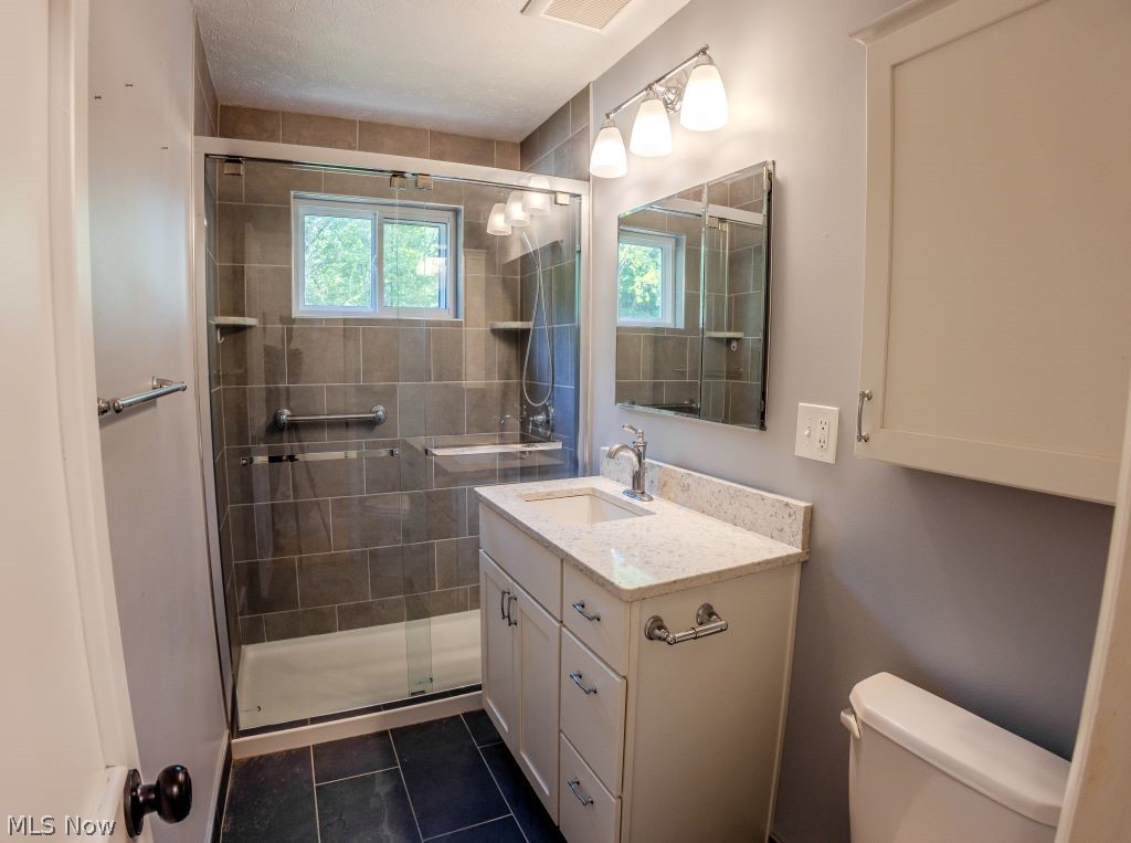 8828 Edgehill Road Mentor, OH 44060 - Photo 9 of 24 Bathroom featuring a shower with shower door, vanity, tile floors, and toilet
