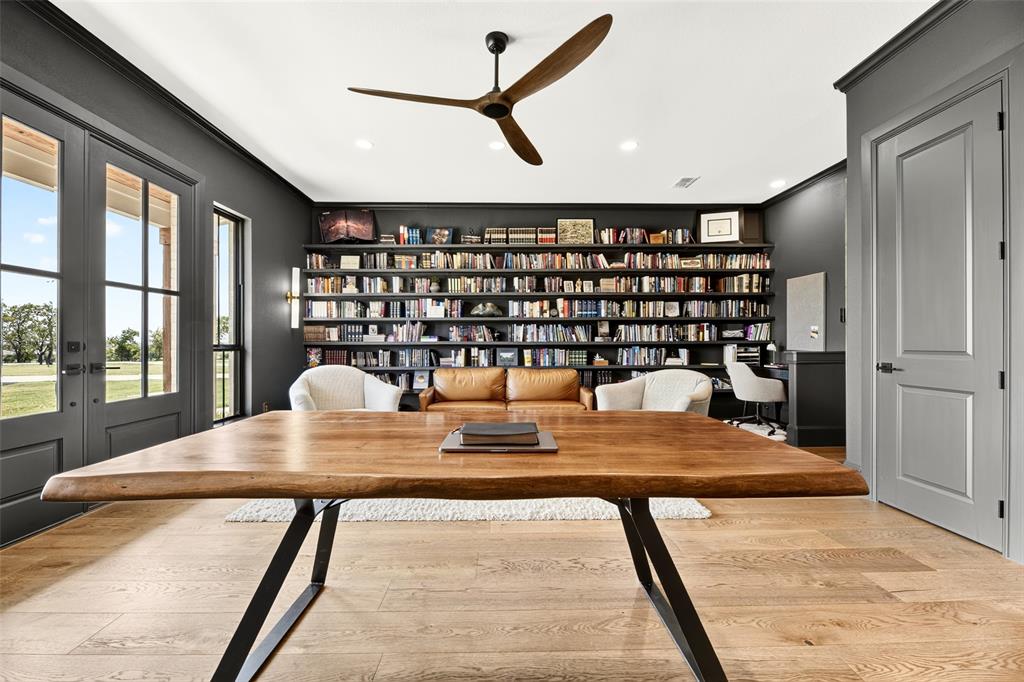 10932 Gregory Road Sanger, TX 76266 - Photo 29 of 40 Wood-finish flooring with a natural grain, full-height built-in shelving, glass-paneled double doors, and a ceiling fan with wood-tone blades