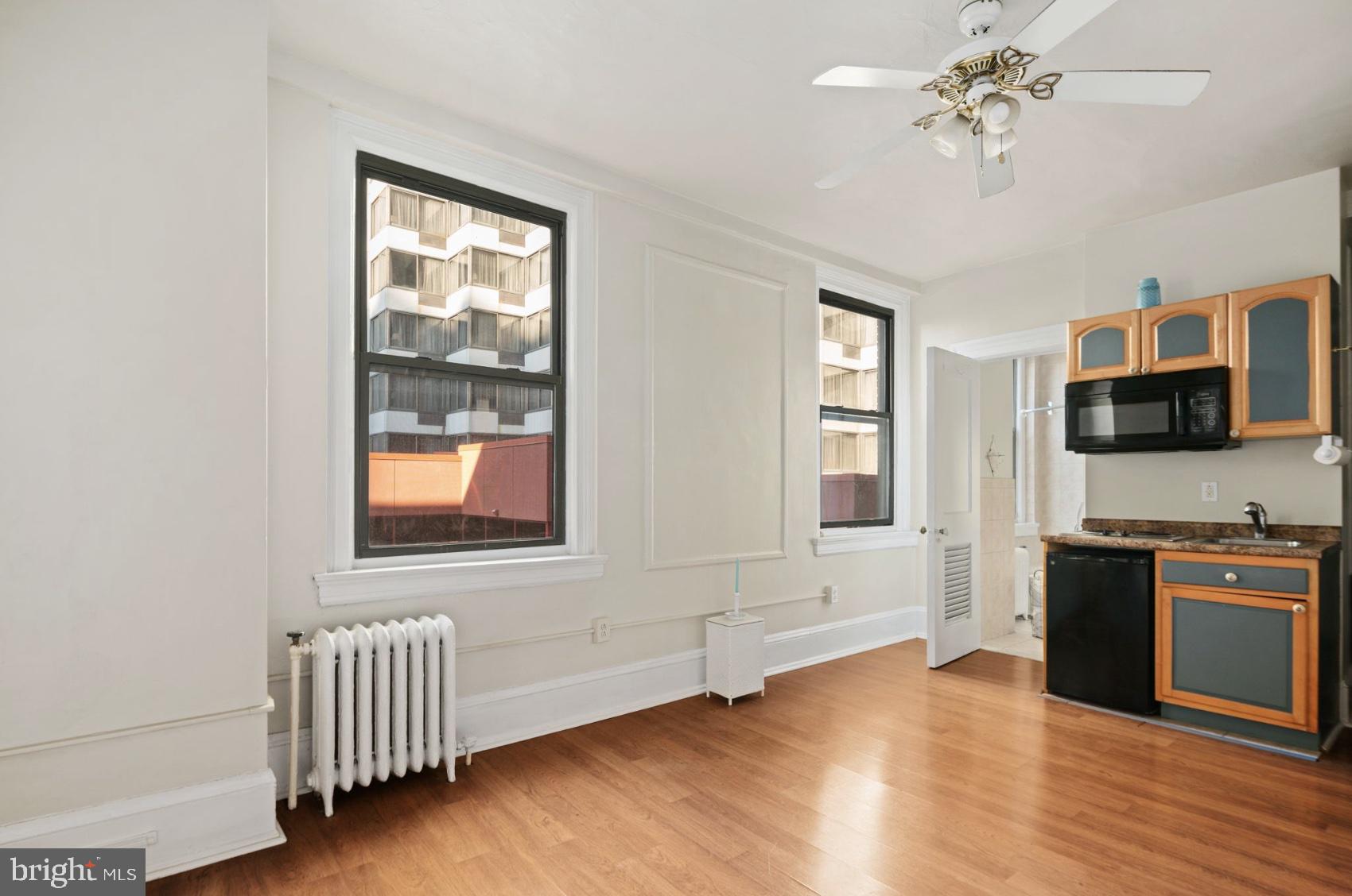 1324 Locust Street, Unit 619 Philadelphia, PA 19107 - Photo 5 of 19 a view of a livingroom with a flat screen tv wooden floor and a window