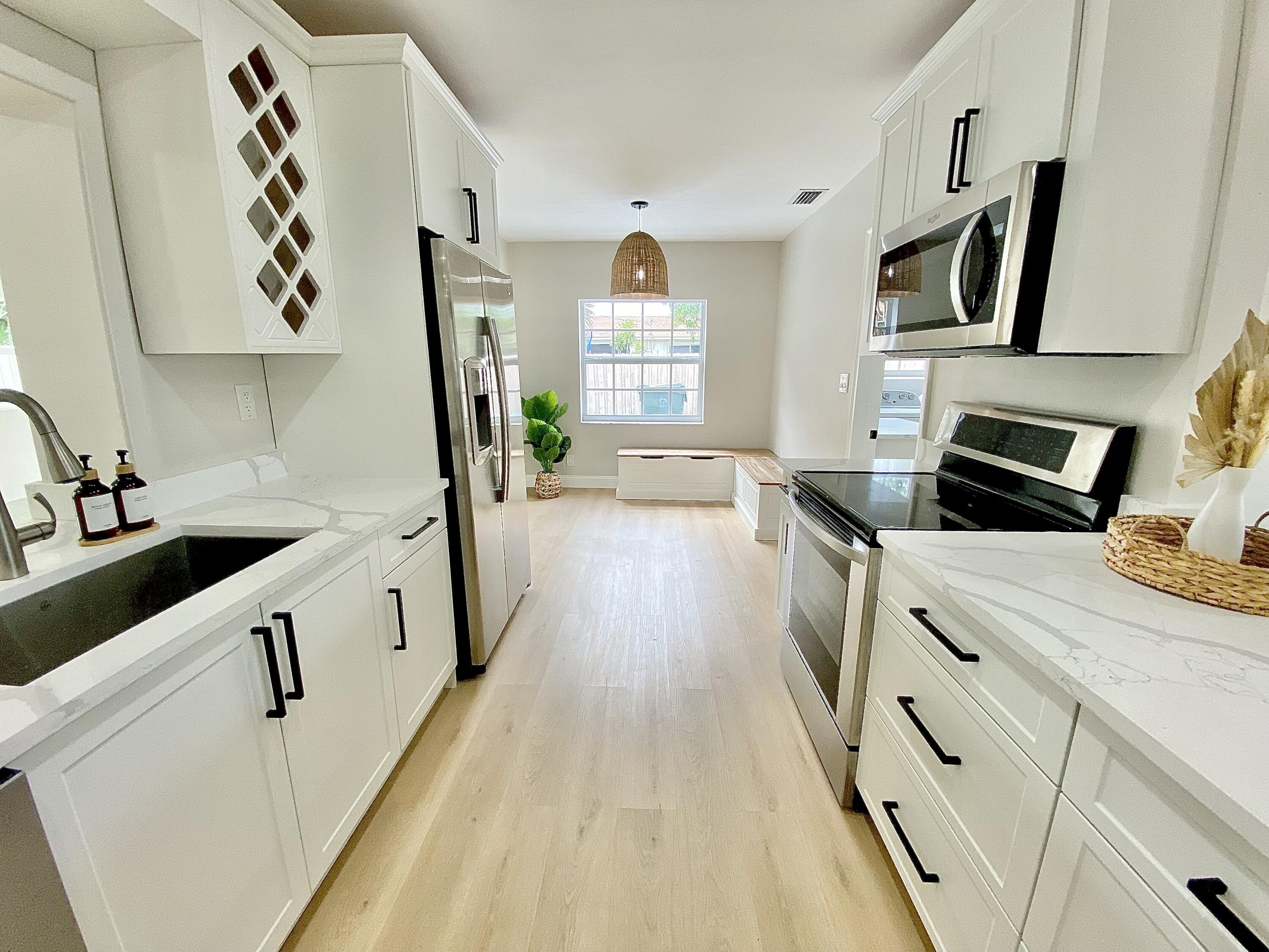 500 Southwest 3rd Avenue Boca Raton, FL 33432 - Photo 21 of 39 a kitchen with granite countertop a sink a stove top oven a refrigerator and cabinets