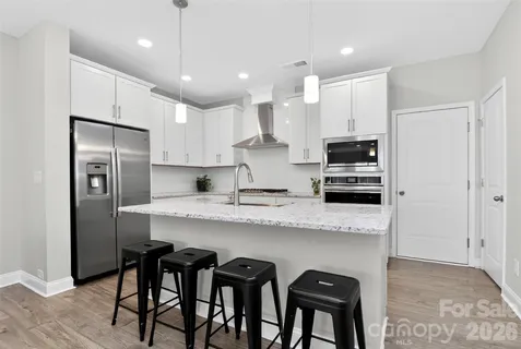 a kitchen with stainless steel appliances granite countertop a dining table chairs refrigerator and microwave
