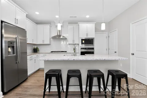 a kitchen with stainless steel appliances granite countertop a table chairs refrigerator and microwave