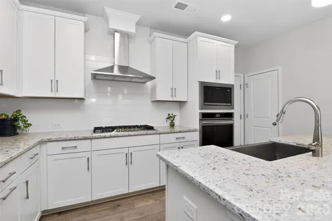 a kitchen with granite countertop white cabinets and stainless steel appliances