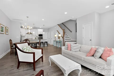 a living room with furniture kitchen view and a wooden floor