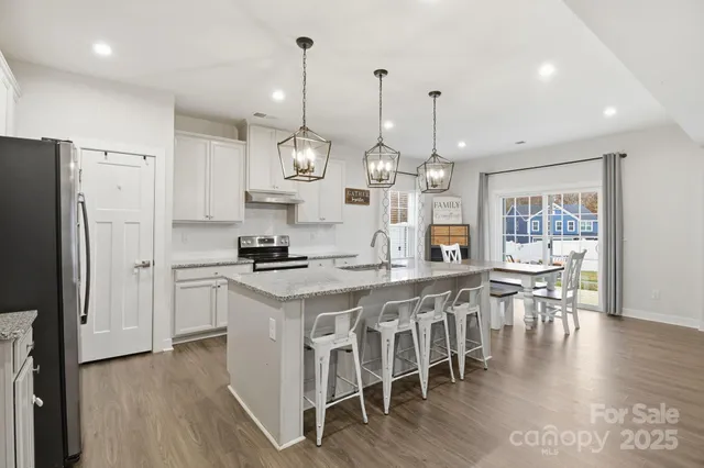 an open kitchen with wooden floor and stainless steel appliances
