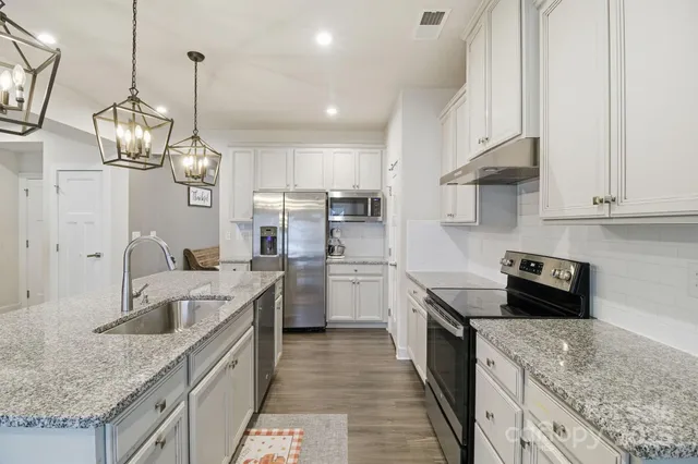 a kitchen with stainless steel appliances granite countertop a sink stove and refrigerator