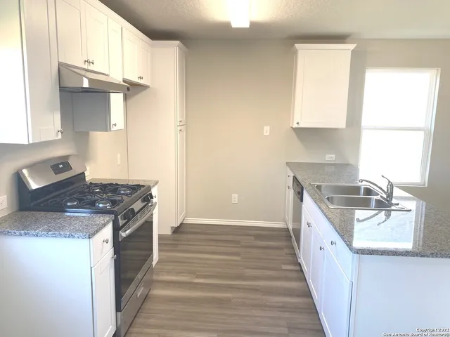 a kitchen with a sink stove top oven and cabinets