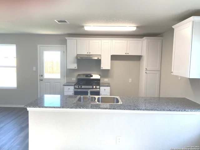 a kitchen with kitchen island granite countertop a stove a refrigerator and a sink