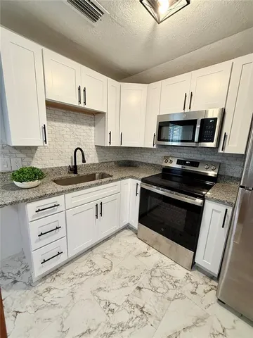 a kitchen with stainless steel appliances kitchen island granite countertop a sink stove and cabinets