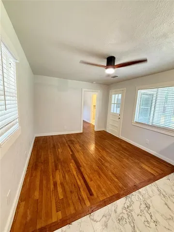 a view of empty room with wooden floor and fan