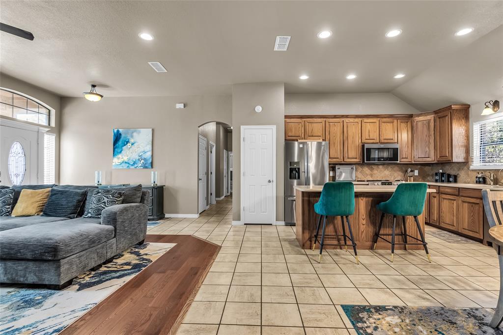 226 King George Road Ponder, TX 76259 - Photo 37 of 39 Kitchen with brown cabinets, open floor plan, light tile patterned floors, a kitchen island, and a breakfast bar area