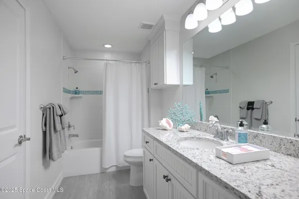 a bathroom with a granite countertop sink a toilet and a mirror