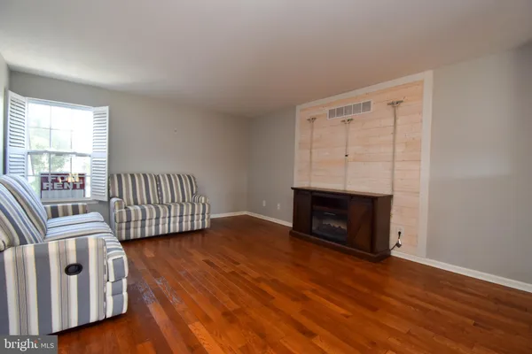an empty room with wooden floor fireplace and windows