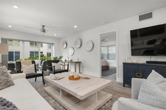 a living room with furniture a flat screen tv and kitchen view