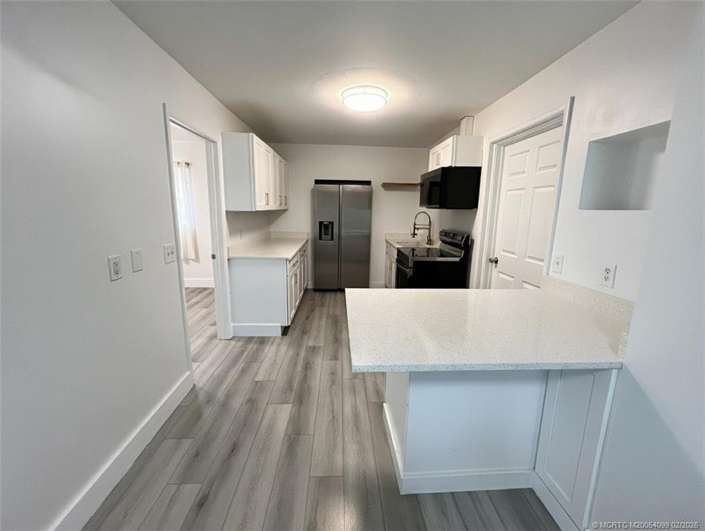 808 Southwest 33rd Street Palm City, FL 34990 - Photo 6 of 13 a large white kitchen with wooden floor and electronic appliances