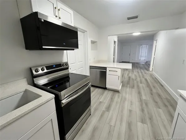 a kitchen with a stove a microwave and white cabinets