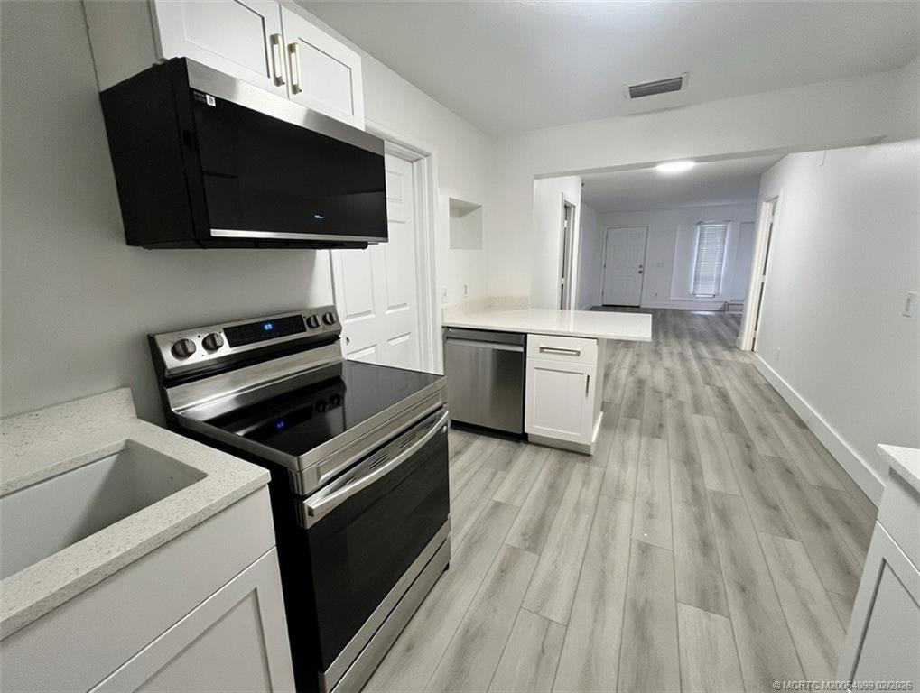 808 Southwest 33rd Street Palm City, FL 34990 - Photo 7 of 13 a kitchen with a stove a microwave and white cabinets