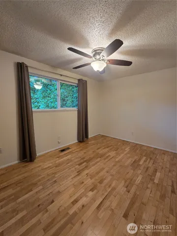a view of empty room with wooden floor and fan