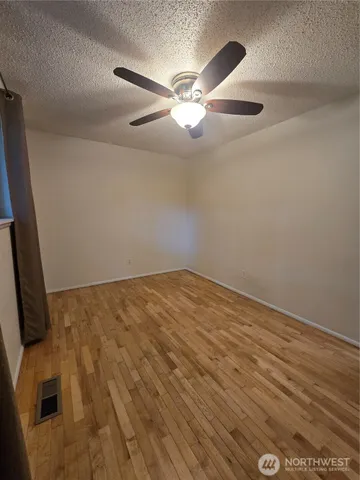 an empty room with wooden floor and fan