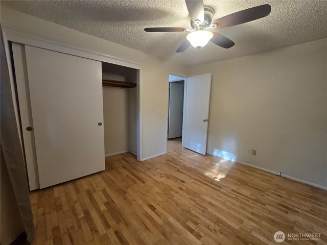 a view of empty room with wooden floor and fan