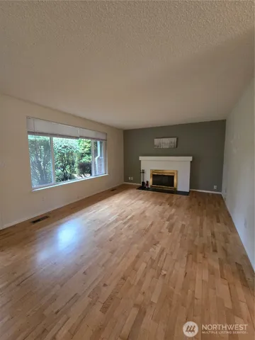 a view of empty room with wooden floor and window