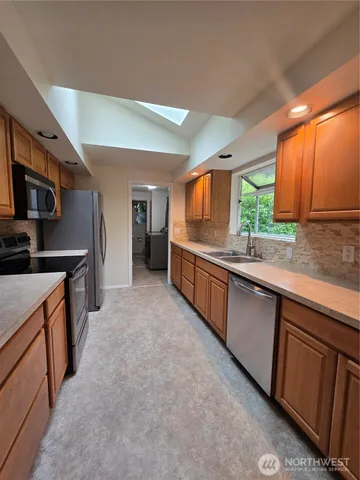 a large kitchen with stainless steel appliances kitchen island granite countertop a sink and cabinets