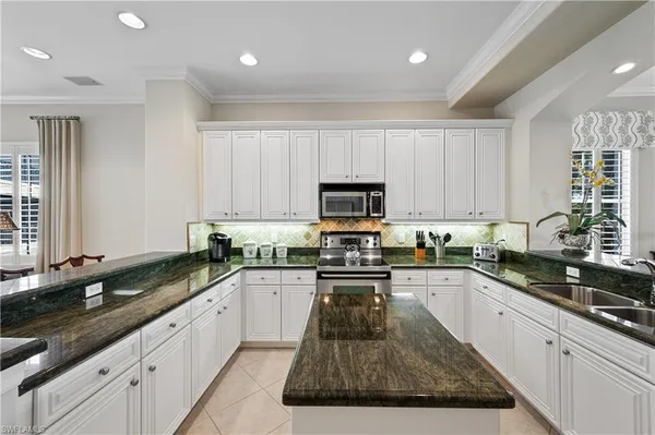 a kitchen with granite countertop a sink a counter top space appliances and cabinets