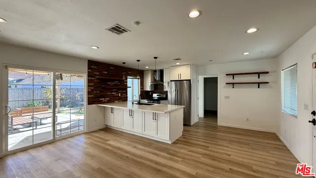 a kitchen with white cabinets and wooden floor