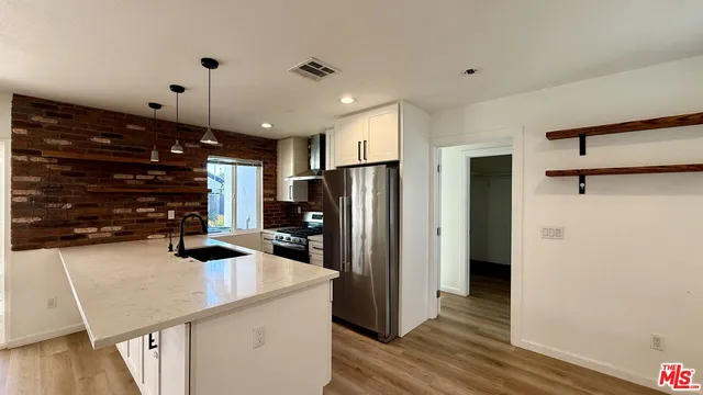 a kitchen with stainless steel appliances a refrigerator and a wooden floor