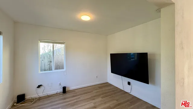 a view of an empty room with wooden floor and windows