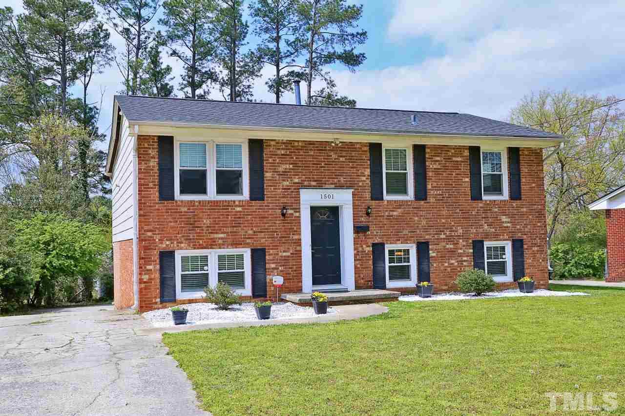 1501 Westchester Road Raleigh, NC 27610 - Photo 1 of 25 front view of a brick house with a yard a large window and a table and chairs