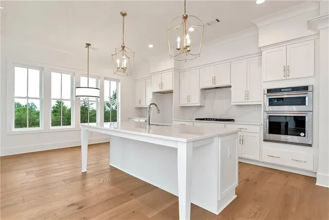 a large white kitchen with granite countertop a large window and stainless steel appliances