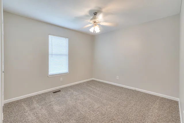 an empty room with windows and chandelier fan