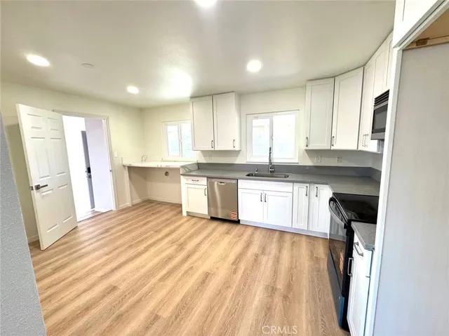 a kitchen with white cabinets appliances and a window