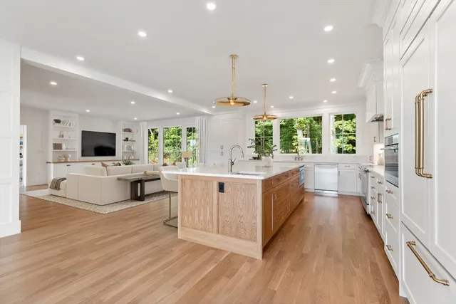 a large white kitchen with a large counter top and stainless steel appliances