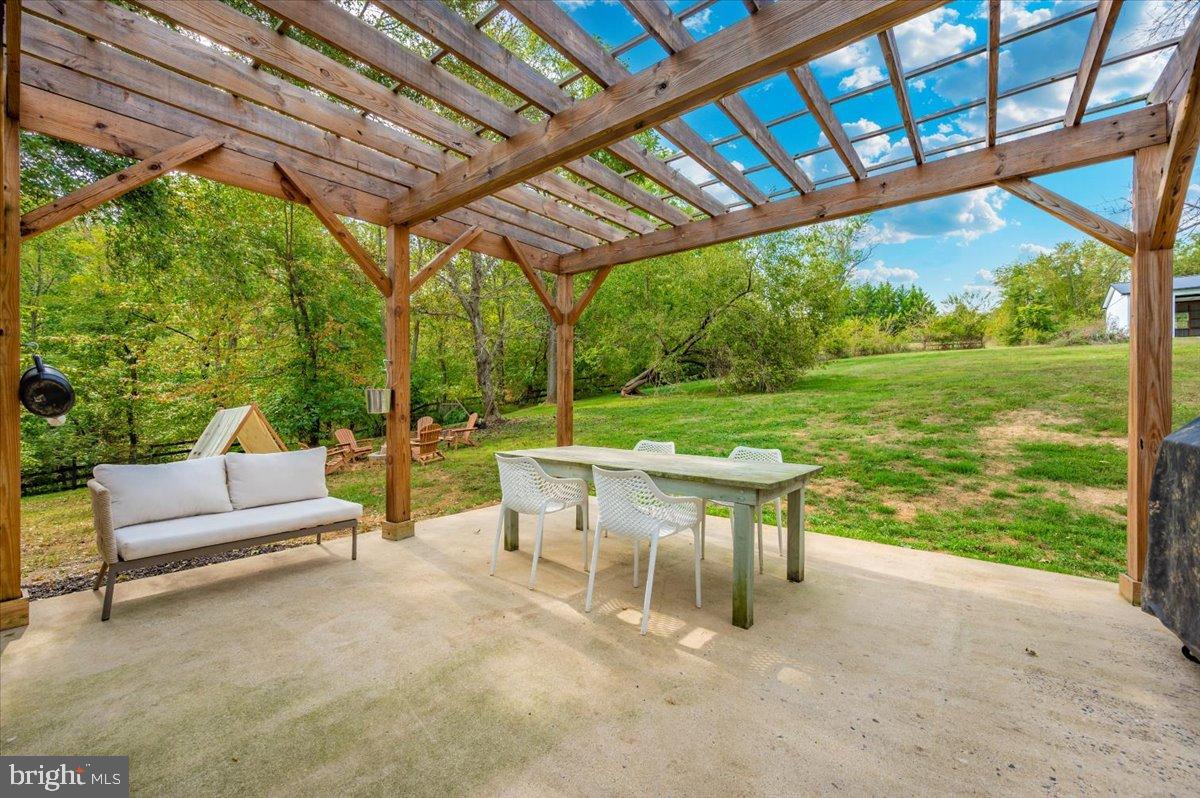 2710 Monument Road Myersville, MD 21773 - Photo 48 of 79 Serene outdoor dining under a wooden pergola.