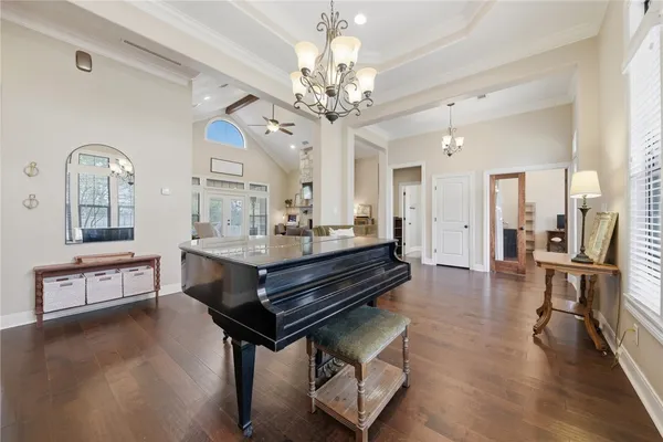 a spacious bedroom with a large bed a chandelier and windows