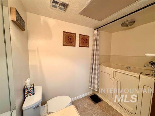 3197 Neeley Road American Falls, ID 83211 - Photo 18 of 45 Bathroom featuring a walk-in tub with grab bars, a toilet, and light-toned wall paint