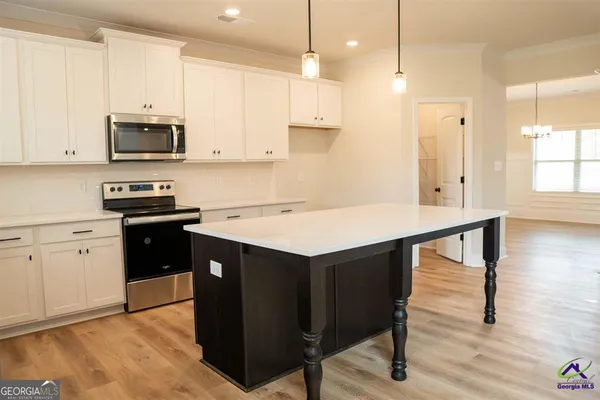 a kitchen with stainless steel appliances kitchen island a table chairs sink and cabinets